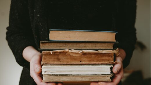 a person holding a stack of books in their hands